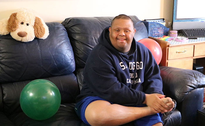 young man sitting on a sofa next to a balloon