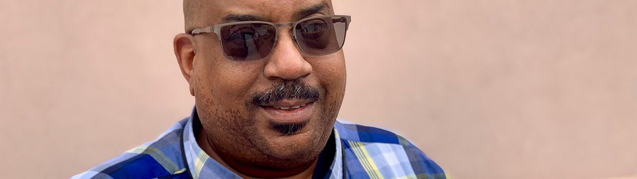 a man is wearing sunglasses and a blue, plaid shirt