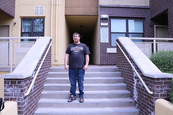 a young man standing on the steps of a brick building