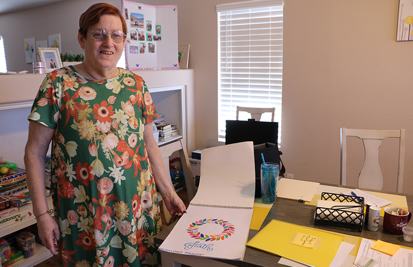 woman holding a sketchpad opened to a page with floral artwork