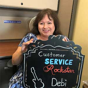 woman holding sign that reads "Customer Service Rockstar Debi"