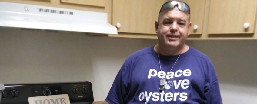 a man wearing a purple t-shirt that reads "peace love oysters"