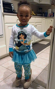Toddler in fancy skirt standing in mom’s high heeled shoes