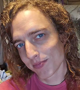 White male with blue eyes and brown extremely curly hair.