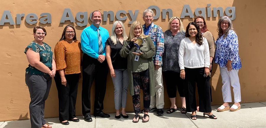 a group of people standing before a sign that reads "Area Agency on Aging"