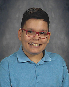 A boy wearing a new, blue, polo shirt smiles for his school photo