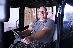 a man sitting in golfcart with his hands on the steering wheel