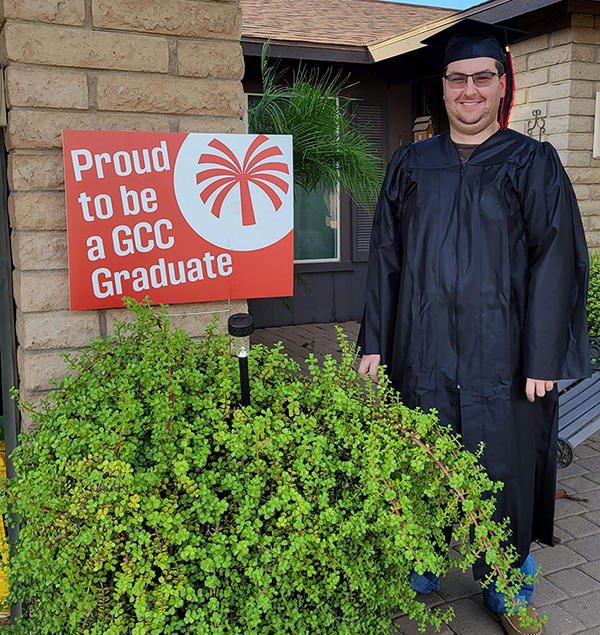 a young man wearing a black cap and gown standing in front of a house