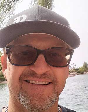 a man wearing a baseball cap and sunglasses is smiling