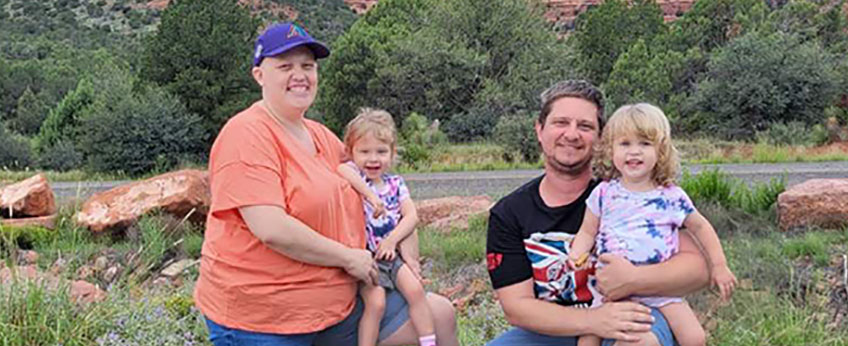 woman, man and two small children standing before a scenic red mountain view