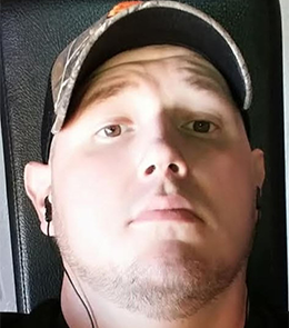 White male with brown eyes and bald head.