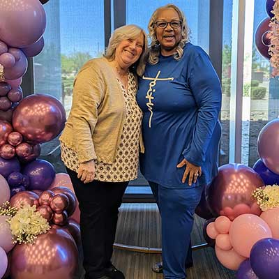 two women standing under a balloon arch