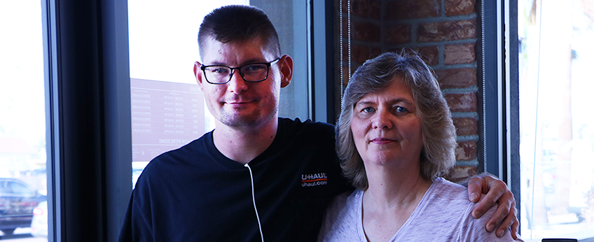 a man has an arm around his mother; they are smiling for the camera