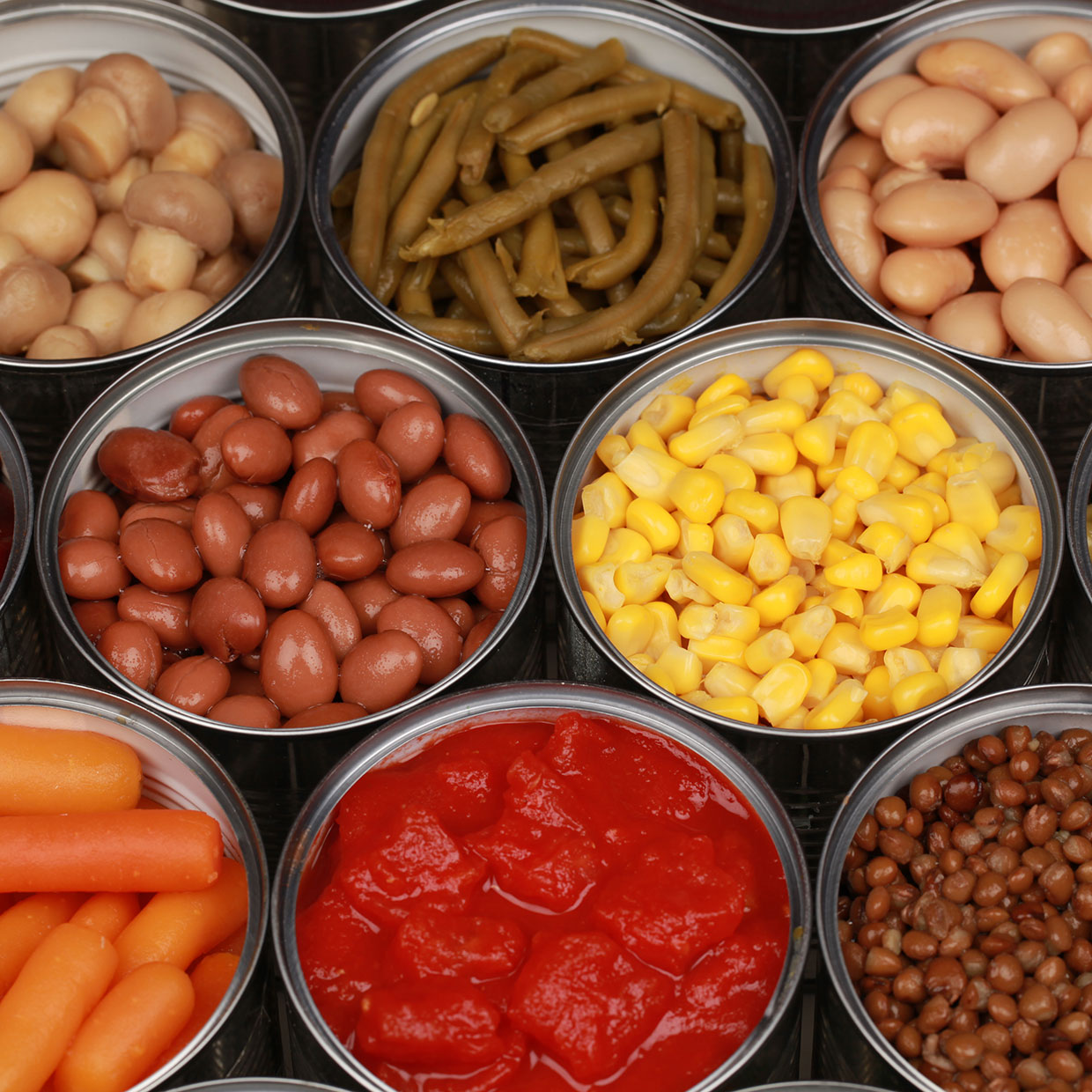 a group of opened cans of food containing fruits vegetables and legumes