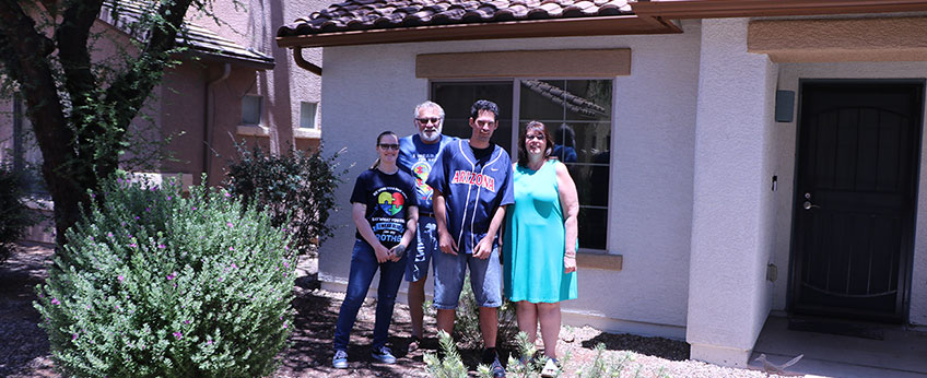 family of four posing for a photo in front of their house