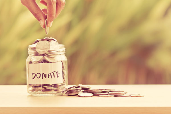 a hand drops a coin into a jar labeled "donate"