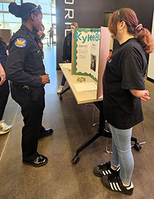 a police officer looks at poster at job fair booth