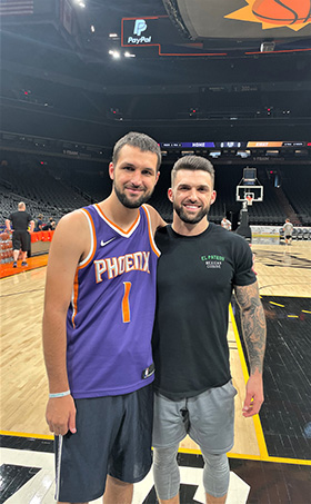 two young men standing on a basketball court
