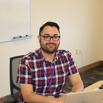 a man sits at a desk smiling for the camera