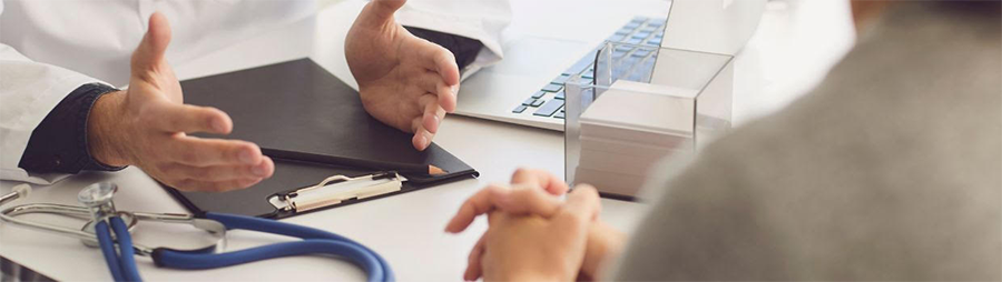 Doctor and patient sitting at a desk with a folder and stethoscope.