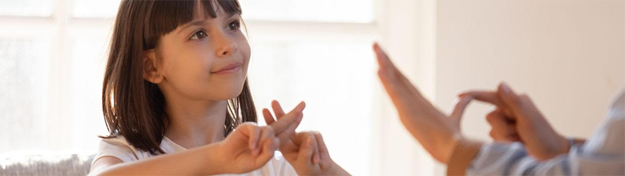 A young girl and an adult engaging in sign language communication.