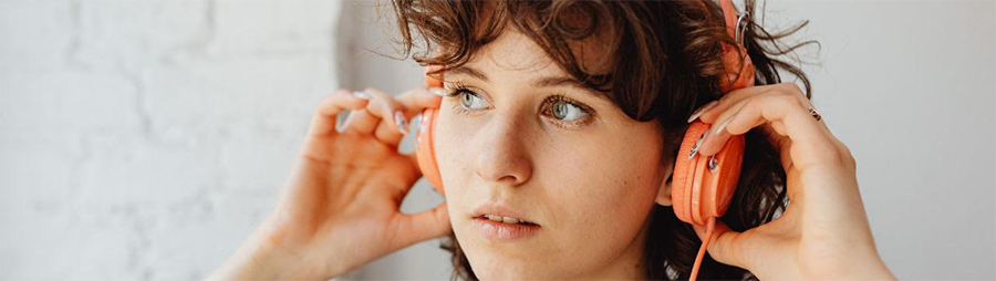 Close-up of a person adjusting bright orange headphones.