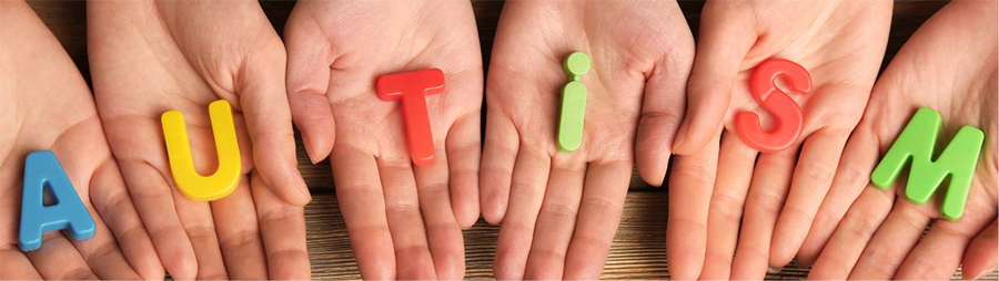 Hands holding plastic letters that spell out Autism