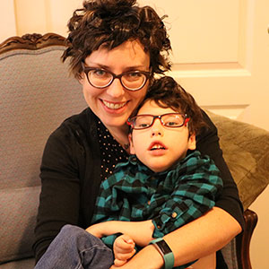 Sitting in an easy chair, a mother cuddles her five-year-old son.