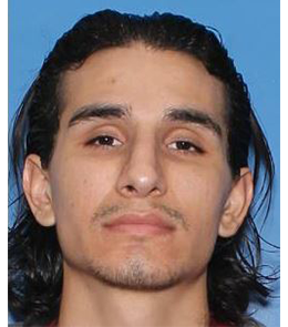 A Hispanic man with brown eyes, long black hair, and mustache and beard stubble