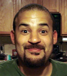 A White male with brown eyes, black hair, mustache and goatee