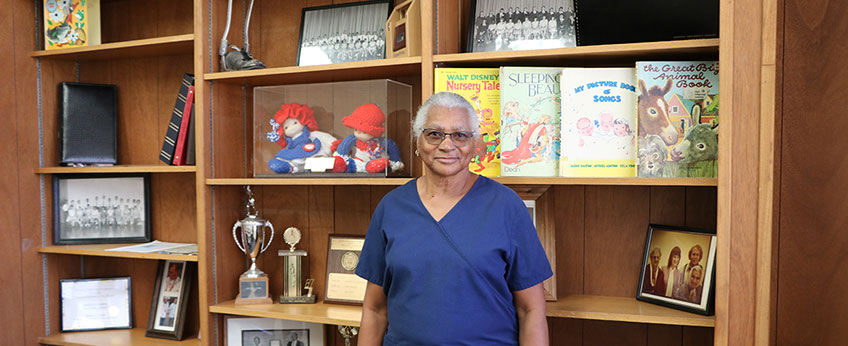 a woman stands in front of a bookcase