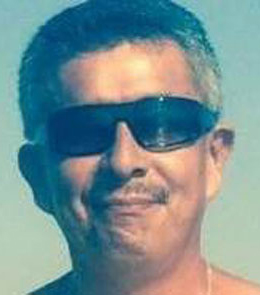 A Hispanic man with short, grey hair and a black mustache is wearing sunglasses.
