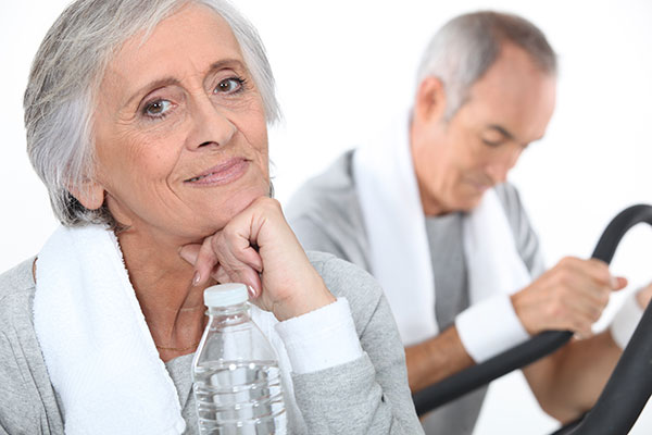 Senior citizen male and female exercising in gymnasium