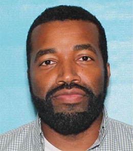 A Black male with brown eyes, brown hair, mustache and beard.
