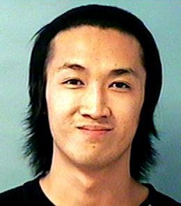 An Asian man with long, black hair and brown eyes is wearing a black shirt.