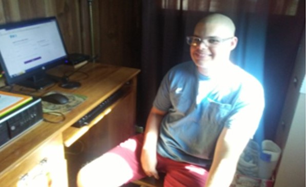 Young man turns away from his computer to give us a smile.