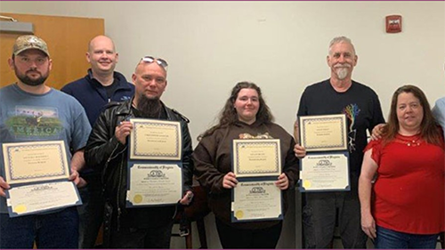 People standing in a room holding certificates.