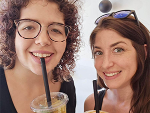 Two women smiling and holding drinks.