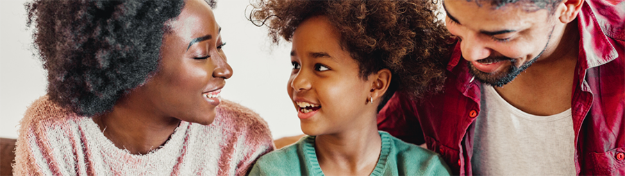 Two adults and a child smile at each other.