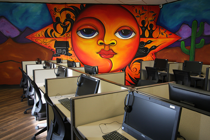a computer lab; a mural of a bright desert scene is visible on a wall