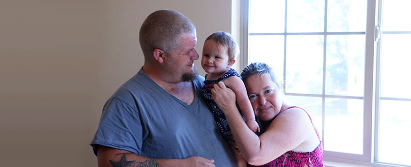 a family - dad, 10-month-old daughter and mom - snuggle together