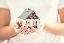 Small home model being held in a person's hands.