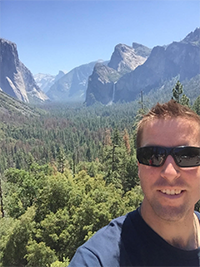 Man taking a selfie with a mountainous landscape in the background.