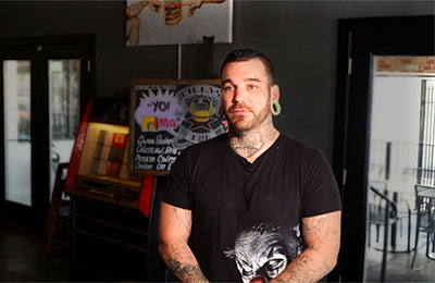 a man wearing a black t-shirt stands inside a restaurant