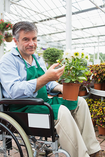 Man in a wheelchair works as a gardener 