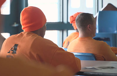 men in orange shirts sitting in a classroom