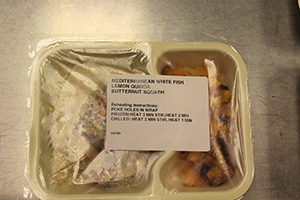 a packaged meal with label on top that reads "Mediterranean White Fish, Lemon Quinoa, Butternut Squash"