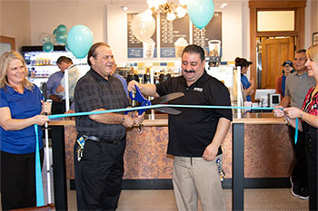 a man cuts a ribbon at a cafeteria grand opening