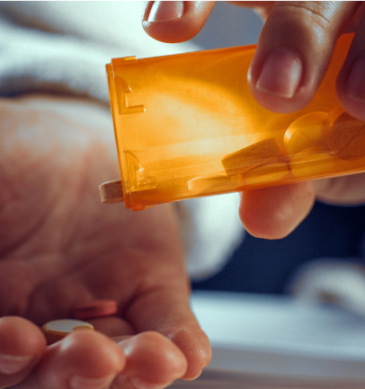 Person shaking a pill out of a medicine bottle.