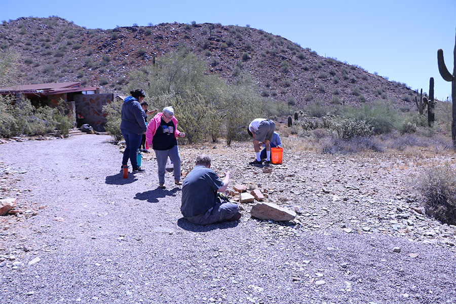 Woman in a pink jacket is one of six adults collecting rocks in the desert at Taliesin West in Scottsdale.